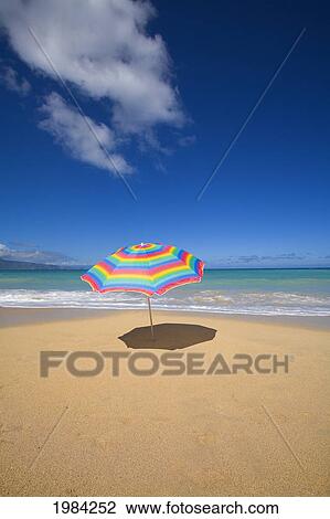 Stock Image - Brightly Colored Beach Umbrella On The Sand Near The Ocean.. Fotosearch