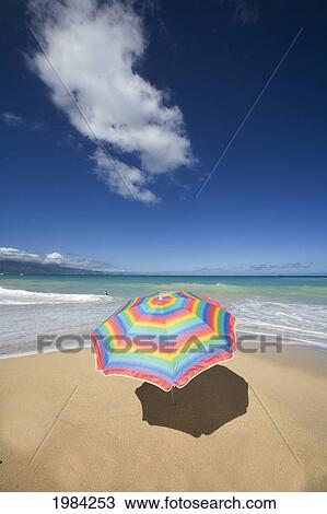 Stock Image - Brightly Colored Beach Umbrella On The Sand Near The Ocean.. Fotosearch