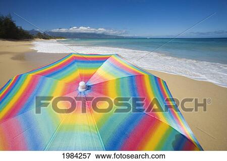 Brightly Colored Beach Umbrella On The Sand Near The Ocean. View Large Photo Image Stock Photo - Brightly Colored Beach Umbrella On The Sand Near The Ocean.. Fotosearch