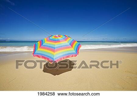 Stock Photo - Brightly Colored Beach Umbrella On The Sand Near The Ocean.. Fotosearch