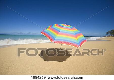 Brightly Colored Beach Umbrella On The Sand Near The Ocean. View Large Photo Image Stock Photo - Brightly Colored Beach Umbrella On The Sand Near The Ocean.. Fotosearch