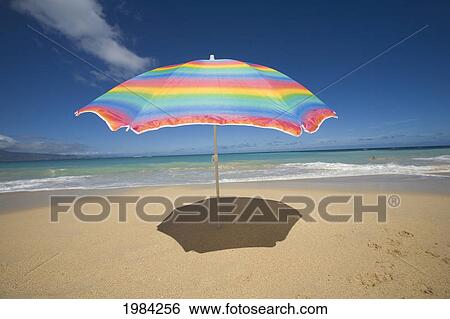 Brightly Colored Beach Umbrella On The Sand Near The Ocean. View Large Photo Image Stock Photograph - Brightly Colored Beach Umbrella On The Sand Near The Ocean.. Fotosearch