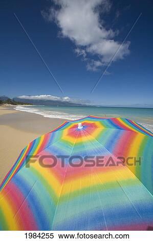 Stock Photography - Brightly Colored Beach Umbrella On The Sand Near The Ocean.. Fotosearch