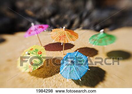 Stock Photo - Colorful Cocktail Umbrellas Stuck In The Sand Of A Tropical Beach.. Fotosearch