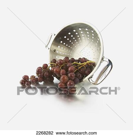 Stock Image - Grapes spilling out of a colander. Fotosearch