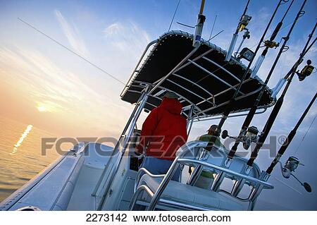 Man driving a boat at sunset with fishing rods in a row; northern east coast united states of america View Large Photo Image Stock Image - Man driving a boat at sunset with fishing rods in a row; northern east coast united states of america. Fotosearch
