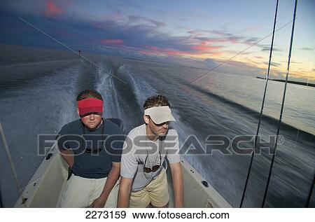 Men riding on a boat at sunset; north carolina united states of america View Large Photo Image Stock Photo - Men riding on a boat at sunset; north carolina united states of america. Fotosearch