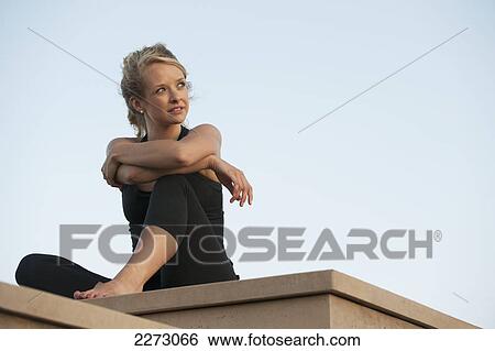 Stock Photograph - Portait of a woman sitting on a ledge; arvada colorado united states of america. Fotosearch