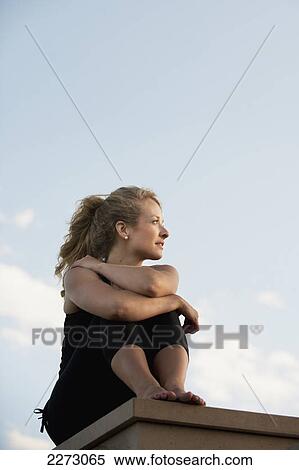 Portait of a young woman sitting on a ledge; arvada colorado united states of america View Large Photo Image Stock Photography - Portait of a young woman sitting on a ledge; arvada colorado united states of america. Fotosearch