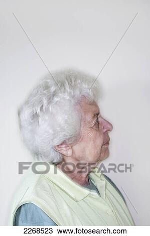 Stock Image - Portrait of a senior woman standing against a white wall looking sideways; toronto ontario canada. Fotosearch