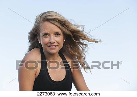 Stock Photo - Portrait of a woman with long blond hair against a blue sky; arvada colorado united states of america. Fotosearch