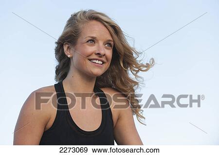 Stock Photo - Portrait of a woman with long blond hair against a blue sky; arvada colorado united states of america. Fotosearch