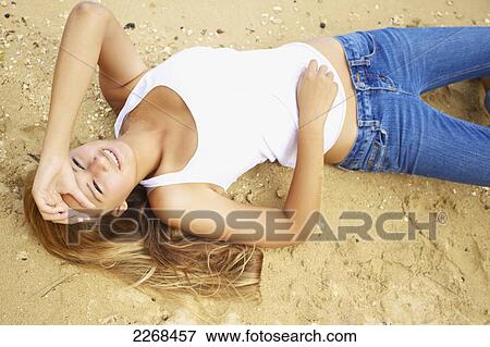 Portrait of a young woman laying on the sand; kauai hawaii united states of america View Large Photo Image Stock Photo - Portrait of a young woman laying on the sand; kauai hawaii united states of america. Fotosearch