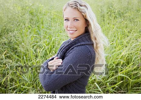 Picture - Portrait of a young woman standing in a grass field; hawaii united states of america. Fotosearch