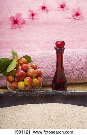 Stock Image - Spa Elements, A Bowl Filled With Sand And Pink Towel, Bowl Of Fruit, Flowers And Glass Bottle.. Fotosearch