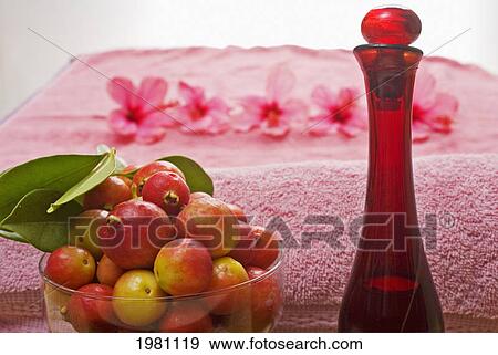 Stock Photo - Spa Elements, A Pink Towel, Bowl Of Fruit, Glass Bottle And Line Of Flowers Blurred In Background.. Fotosearch