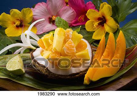 Stock Image - Studio Shot Of A Variety Of Tropical Fruit Served On A Ti Leaf With Flowers.. Fotosearch