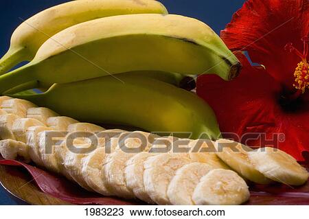 Stock Image - Studio Shot Of Bananas, Whole And Cut Into Slices, With Flowers.. Fotosearch