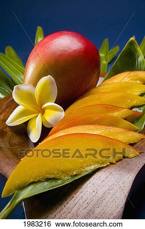 Stock Photograph - Studio Shot Of Mango, Whole And Cut Into Slices, With Flowers.. Fotosearch