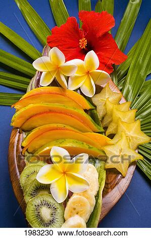Stock Image - Studio Shot Pf A Variety Of Tropical Fruit Sliced On A Platter, With Flowers.. Fotosearch