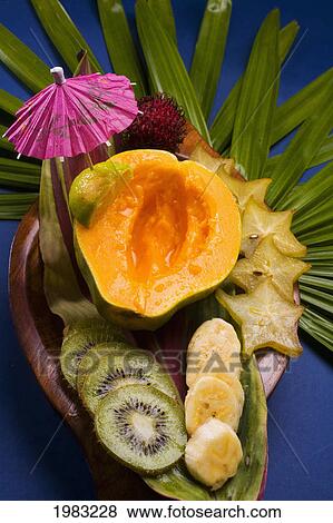 Stock Photo - Studio Shot Pf A Variety Of Tropical Fruit Sliced On A Platter, With Cocktail Umbrella.. Fotosearch