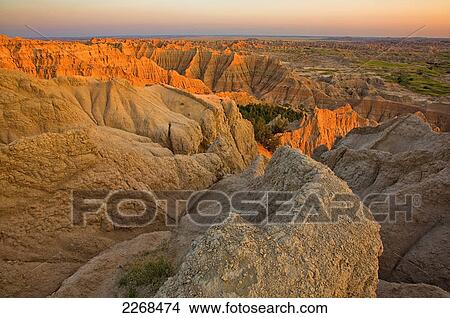 Picture - The setting sun lights up the formations in badlands national park as seen from the pinnacles lookout; south dakota united states of america. Fotosearch