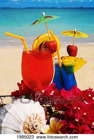 Stock Image - Tropical Cocktails Garnished With Flowers And Fruit On The Beach.. Fotosearch