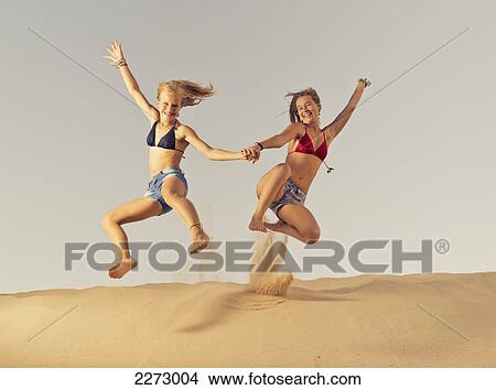 Two girls jumping in the sand; tarifa cadiz andalusia spain View Large Photo Image Picture - Two girls jumping in the sand; tarifa cadiz andalusia spain. Fotosearch