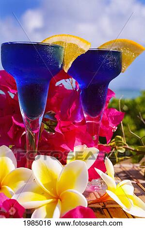 Stock Photograph - Two Tropical Cocktails Garnished With Flowers In Outdoor Setting.. Fotosearch