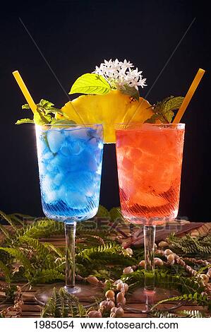 Picture - Two Tropical Drinks Garnished With Fruit And Flowers.. Fotosearch