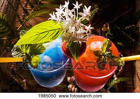 Stock Image - Two Tropical Drinks Garnished With Fruit And Flowers.. Fotosearch