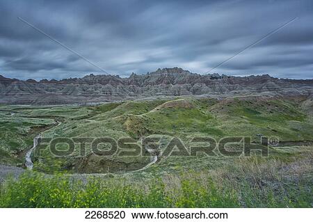 Stock Image - Winding stream through the badlands national park clouds blurred due to long exposure; south dakota united states of america. Fotosearch