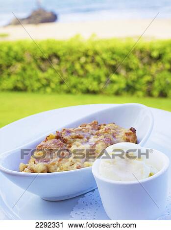 Stock Image - A food item served in a white serving dish with a view of the beach and ocean; Hawaii united states of america. Fotosearch