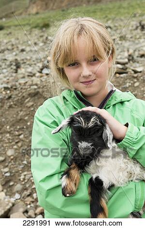 Stock Image - A girl holding a young goat; Shannan xizang china. Fotosearch