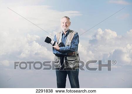 A male photographer holding his camera with clouds and blue sky in the background; Malaga andalusia spain View Large Photo Image Stock Photo - A male photographer holding his camera with clouds and blue sky in the background; Malaga andalusia spain. Fotosearch