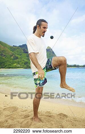 A man bumps his hackey sack with his knee while standing in the sand at the water's edge; Hawaii united states of america View Large Photo Image Stock Image - A man bumps his hackey sack with his knee while standing in the sand at the water's edge; Hawaii united states of america. Fotosearch