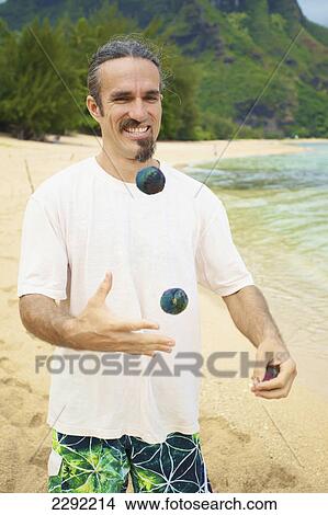 A man juggles with hackey sacks while standing on the beach at the water's edge; Hawaii united states of america View Large Photo Image Picture - A man juggles with hackey sacks while standing on the beach at the water's edge; Hawaii united states of america. Fotosearch