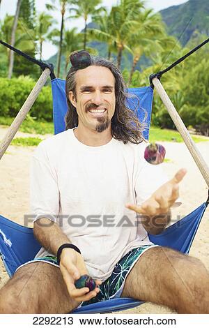 A man juggles with hackey sacks while sitting in a hanging chair on the beach; Hawaii united states of america View Large Photo Image Stock Image - A man juggles with hackey sacks while sitting in a hanging chair on the beach; Hawaii united states of america. Fotosearch