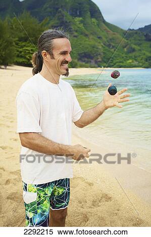 A man juggles with hackey sacks while standing on the beach at the water's edge; Hawaii united states of america View Large Photo Image Stock Photography - A man juggles with hackey sacks while standing on the beach at the water's edge; Hawaii united states of america. Fotosearch