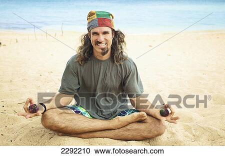 A man sits in the sand in a yoga pose holding two hackey sacks; Hawaii united states of america View Large Photo Image Stock Image - A man sits in the sand in a yoga pose holding two hackey sacks; Hawaii united states of america. Fotosearch