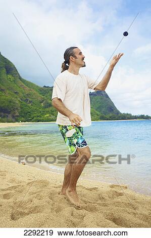 A man throws his hackey sack into the air while standing in the sand at the water's edge; Hawaii united states of america View Large Photo Image Stock Photo - A man throws his hackey sack into the air while standing in the sand at the water's edge; Hawaii united states of america. Fotosearch