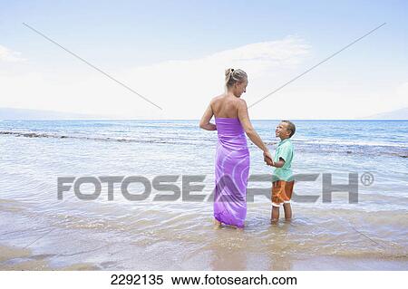 A mother and son hold hands while standing in the shallow water at the ocean; Hawaii united states of america View Large Photo Image Stock Photography - A mother and son hold hands while standing in the shallow water at the ocean; Hawaii united states of america. Fotosearch