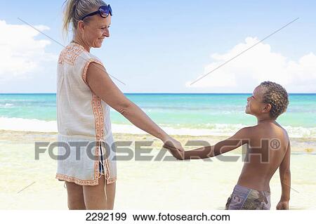 Stock Photo - A mother and son holding hands on the beach; Hawaii united states of america. Fotosearch