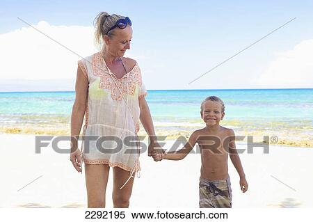 Stock Photography - A mother and son holding hands on the beach; Hawaii united states of america. Fotosearch