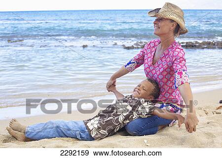 A mother and son on the beach at the water's edge; Hawaii united states of america View Large Photo Image Stock Photo - A mother and son on the beach at the water's edge; Hawaii united states of america. Fotosearch