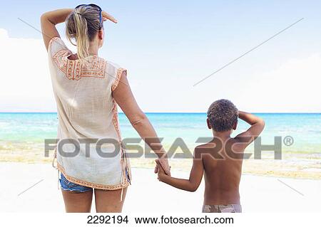 A mother and son standing on the beach looking out at the ocean; Hawaii united states of america View Large Photo Image Picture - A mother and son standing on the beach looking out at the ocean; Hawaii united states of america. Fotosearch