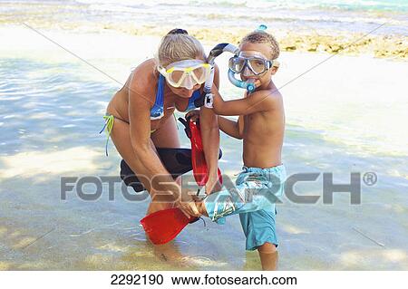 Stock Image - A mother and son with snorkelling gear in the shallow water; Hawaii united states of america. Fotosearch