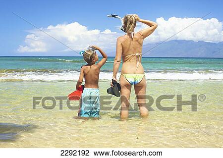 Stock Image - A mother and son with snorkelling gear in the shallow water looking out to the ocean; Hawaii united states of america. Fotosearch