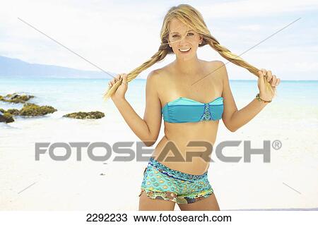 A teenage girl on a beach wearing a two piece bathing suit holding her long hair in braids; Maui hawaii united states of america View Large Photo Image Stock Image - A teenage girl on a beach wearing a two piece bathing suit holding her long hair in braids; Maui hawaii united states of america. Fotosearch