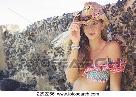 A teenage girl sitting against a rock wall wearing a bikini top and hat; Maui hawaii united states of america View Large Photo Image Stock Photograph - A teenage girl sitting against a rock wall wearing a bikini top and hat; Maui hawaii united states of america. Fotosearch